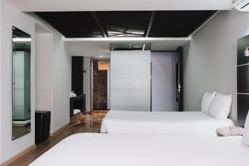 a bedroom with two white beds and a mirror at Exe Cities Reforma in Mexico City