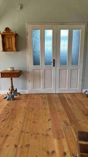 a room with two doors and a wooden floor at Kutscherremise Gut Niendorf - ABC592 - nur Feriengäste! in Bad Kleinen