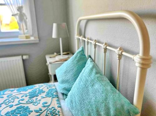 a bed with two blue pillows on top of it at Kutscherremise Gut Niendorf - ABC592 - nur Feriengäste! in Bad Kleinen