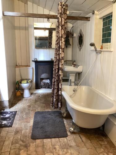 a bathroom with a bath tub and a fireplace at The Eclectic Coach House in Roydon