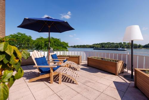 a patio with chairs and a table and an umbrella at Logierhaus RheintorEins in Rees
