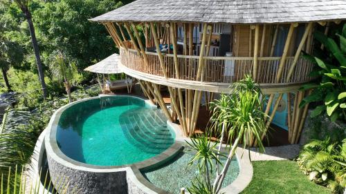 a house with a swimming pool next to a building at Villas Bukit Lipah in Amed