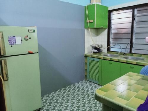 a kitchen with green cabinets and a refrigerator at 51 SpS HOMES in Bagan Serai
