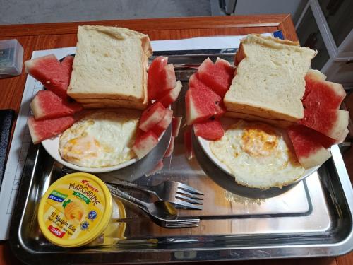 a tray with two plates of eggs and watermelon sandwiches at Little Tay Homestay & Hostel in Làng Lap