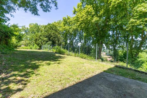 a fence in a yard with trees and grass at Appt moderne refait à neuf in Aire-sur-lʼAdour