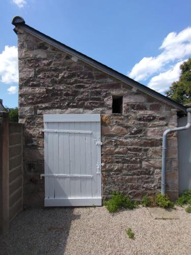 a garage with a white door and a stone wall at Ti Daouzek - Proche plage des Sables-dOr in Plurien