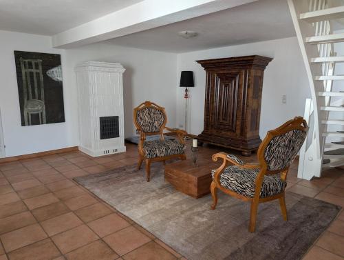 a living room with two chairs and a staircase at Ferienhaus Lisette Wohlfühldomizil zwischen Rebenmeer und Pfälzer Wald in Haßloch