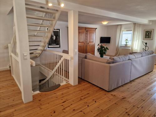 a living room with a couch and a spiral staircase at Ferienhaus Lisette Wohlfühldomizil zwischen Rebenmeer und Pfälzer Wald in Haßloch