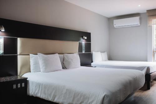 a bedroom with two beds with white pillows at Exe Cities Reforma in Mexico City
