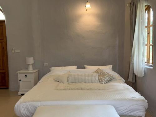 a white bed in a room with a window at Pundin Khaoyai in Nong Sarai