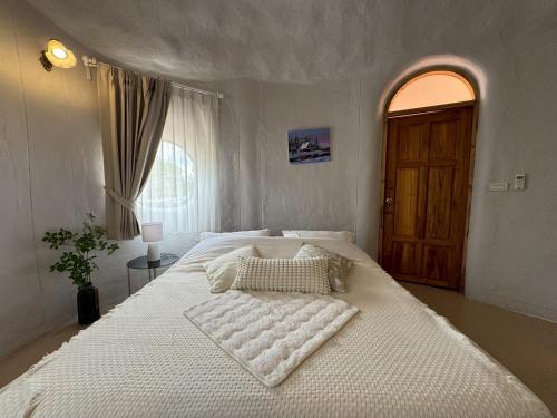 a large white bed in a bedroom with a window at Pundin Khaoyai in Nong Sarai