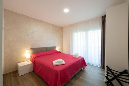 a bedroom with a red bed with a red blanket at Villa Betty Apartments in Arco
