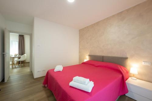 a bedroom with a pink bed with two towels on it at Villa Betty Apartments in Arco