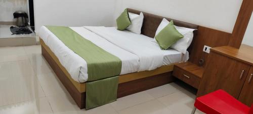 a bedroom with a bed with green and white pillows at Hotel Radhe 