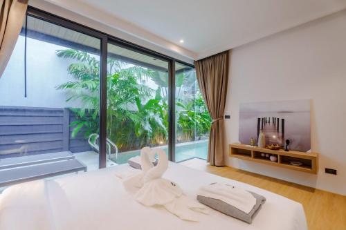 a bedroom with a white bed with a large window at Aileen 3BR Naiton New Private Pool Villa in Ban Sakhu