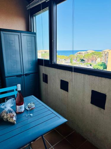 a blue table with a bottle of wine and a glass at Le cosy vue mer in Fleury