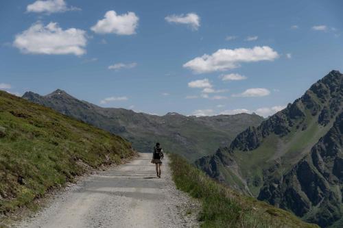 a person walking down a dirt road in the mountains at Heimspitze - Alpenhotel & Wirtshaus in Gargellen