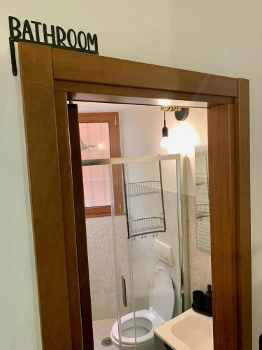 a bathroom with a toilet and a sign on the door at Old Porlezza Apartment in Porlezza