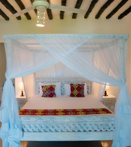 a bedroom with a white bed with a canopy at Pearl Beach by Sansi in Michamvi