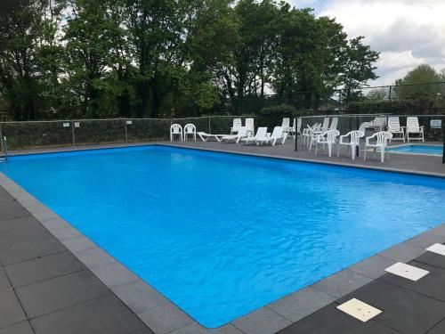 a large blue swimming pool with white chairs and tables at Vakantiehuis in Stavenisse