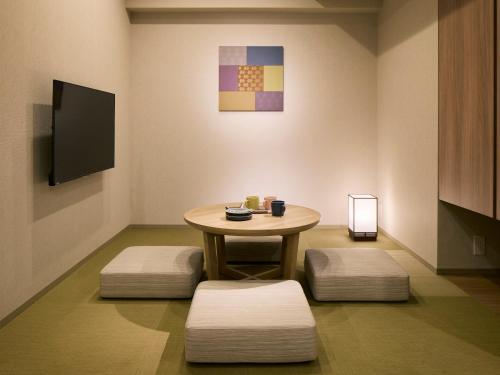 Habitación con mesa, 2 taburetes y TV. en Minn Ueno Shin-Okachimachi, en Tokio