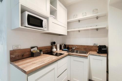 a kitchen with white cabinets and a microwave at La Maison by Quokka 360 - Historic centre of Como - The Walled City in Como