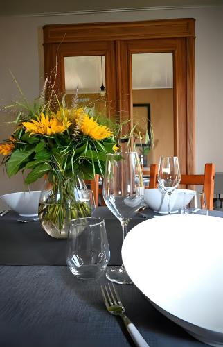 a table with glasses and a vase of yellow flowers at L Orchidée in Dinant