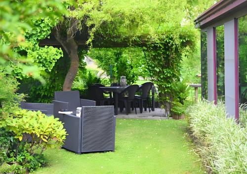 a patio with a table and chairs in a garden at L Orchidée in Dinant
