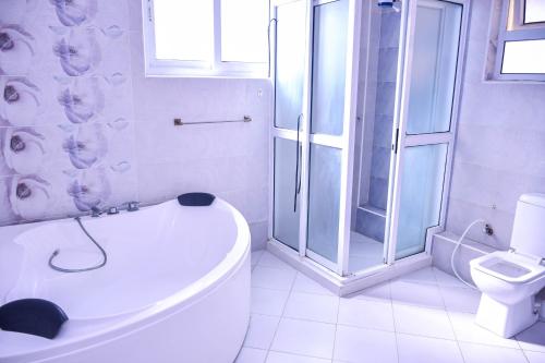 a white bathroom with a shower and a toilet at Iko homes in Mombasa