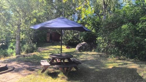 a picnic table with an umbrella and a bench at Hus Björk in Fågelfors