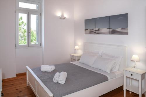 a white bedroom with two towels on a bed at Andros Neoclassical Villa NP1926 with Private Pool in Steniaí