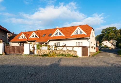 a white house with an orange roof on a street at Penzion U Zámeckého parku in Žihobce