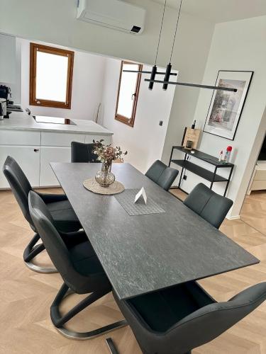 a dining room table with black chairs and a kitchen at Casa Cabini Piave in Eraclea