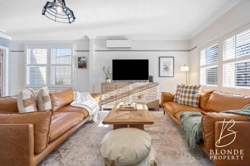 a living room with brown leather furniture and a flat screen tv at Journeyman's Cottage in Ballarat