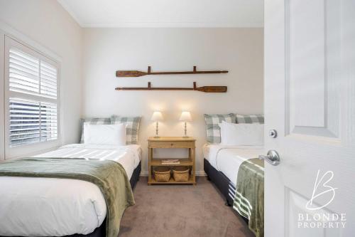 two beds in a small room with a window at Journeyman's Cottage in Ballarat