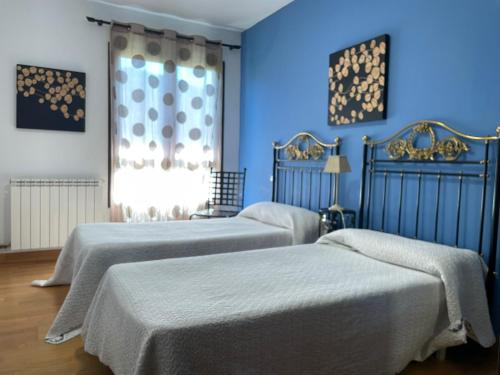 two beds in a room with blue walls at Casa Tau in Larrasoaña
