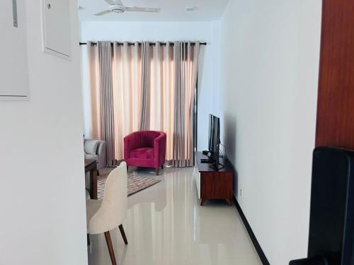 a living room with a red chair and a television at Colombo, Trizen Luxury Apartments, Sri Lanka in Colombo