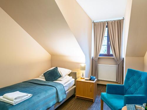 a bedroom with a bed and a blue chair at Zamek w Krasiczynie in Krasiczyn