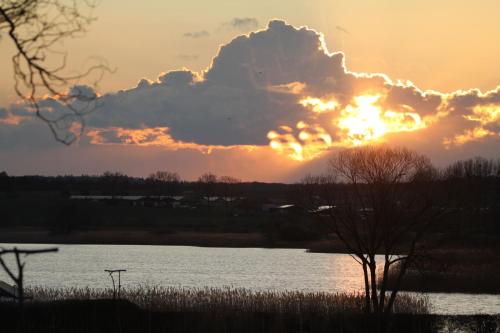 a sunset over a body of water with the sun setting at Ferienhaus Am See In Blankensee Groß Schönfeld in Blankensee