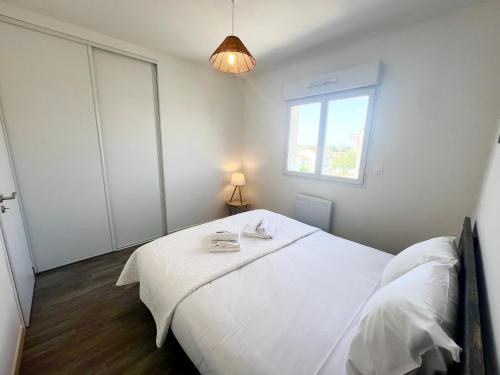 a bedroom with a white bed and a window at Le Spacieux - Royan, Wifi & Balcon in Royan