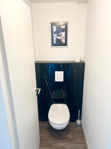 a bathroom with a toilet with a black wall at Le Spacieux - Royan, Wifi & Balcon in Royan