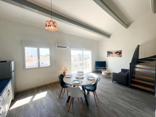 a dining room and living room with a table and chairs at Le Spacieux - Royan, Wifi & Balcon in Royan