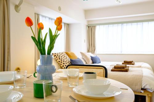 a living room with a table with a vase with orange flowers at Palaisgrace Shibuya - Live Like a Trendy Local in Sangenjaya 三軒茶屋 - Direct Shibuya Access in Tokyo