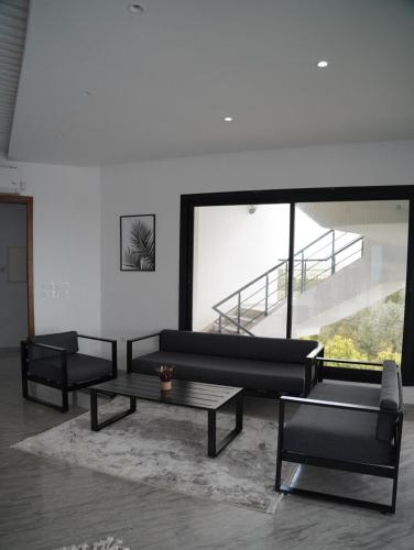a living room with two black couches and a table at Dar El Bondek companion pool jacuzzi forest in Beni Khiar