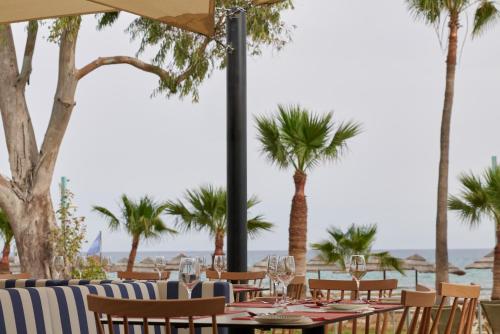 a restaurant with tables and chairs and palm trees at Atlantica Callisto in Ayia Napa