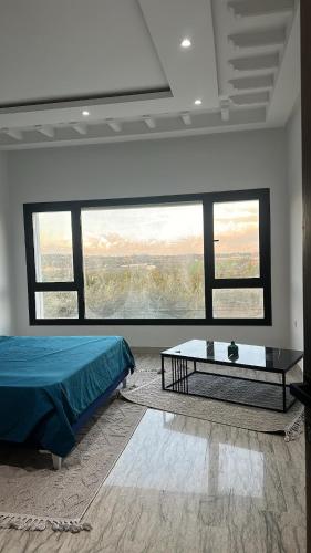 a bedroom with a bed and a table and windows at Dar El Bondek companion pool jacuzzi forest in Beni Khiar