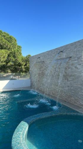 a swimming pool with a water fountain at Dar El Bondek companion pool jacuzzi forest in Beni Khiar