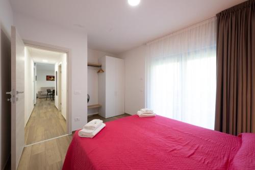 a bedroom with a pink bed with a red blanket at Villa Betty Apartments in Arco