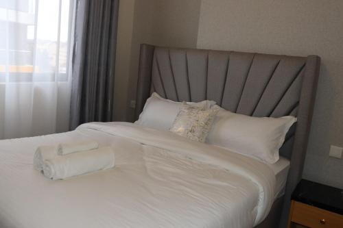 a bed with two rolled towels on top of it at Staylah Sanctuary 1br in Wilma Tower Apartment- Kilimani in Nairobi