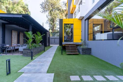 a house with a yellow facade and green grass at Staylah Sanctuary 1br in Wilma Tower Apartment- Kilimani in Nairobi